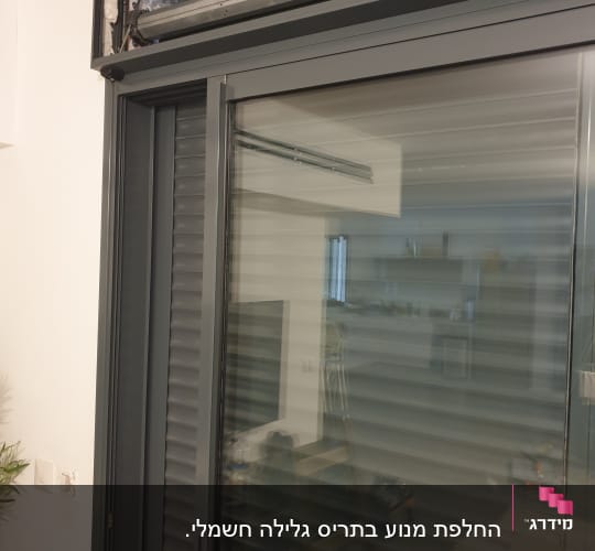 תריסים אפורים מותקנים על מסגרת חלון זכוכית.